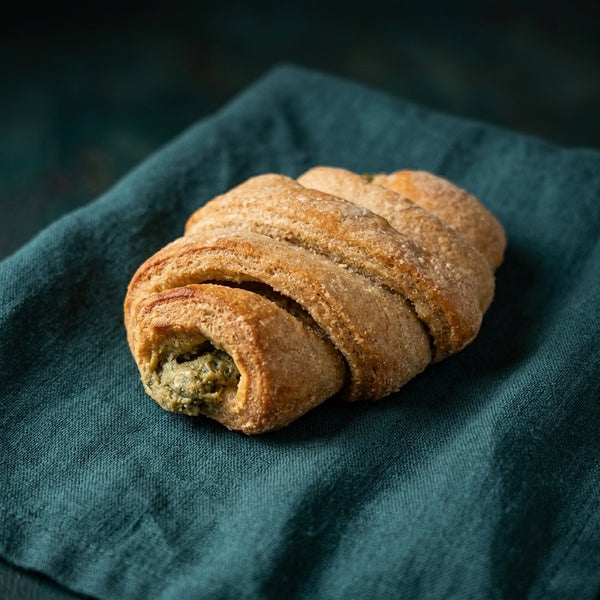 Pisztáciás krémmel töltött croissant sötétzöld háttér előtt.
