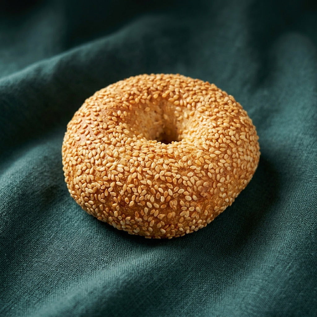 Szezámmagos bagel péksütemény sötétzöld textílián.