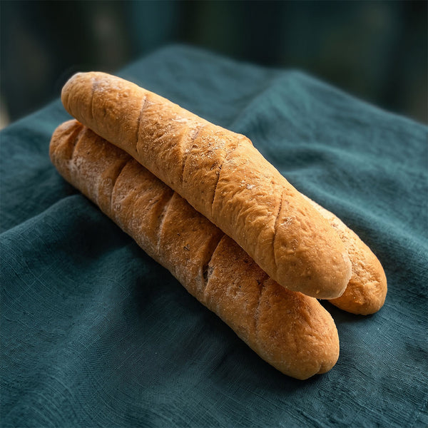 Két darab friss, ropogós fehér bagett sötétzöld szalvétán.