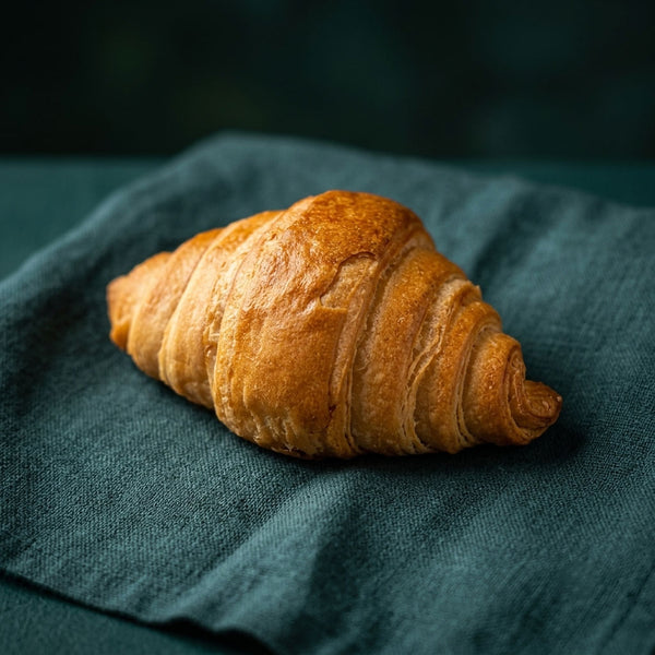 Aranybarna színű, klasszikus formájú barackos croissant.