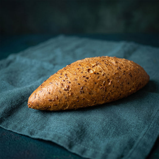 Magvakkal gazdagon megszórt, hosszúkás fitt vekni sötétzöld szalvétán.