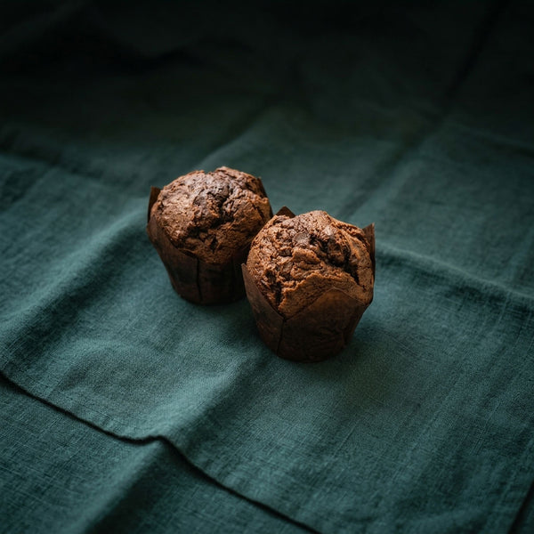 Két darab csokoládés muffin sötétzöld alapon.
