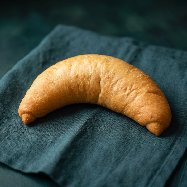 Hagyományos formájú, aranysárga kifli sötétzöld alapon.