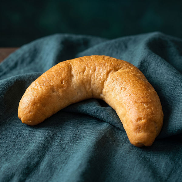 Hagyományos formájú, aranysárga kifli sötétzöld alapon.