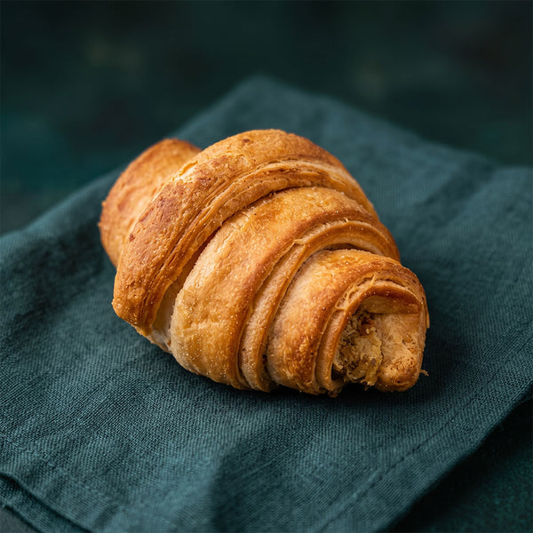 Gazdag, pisztáciás krémtöltelékkel rétegzett, aranyszínű croissant.