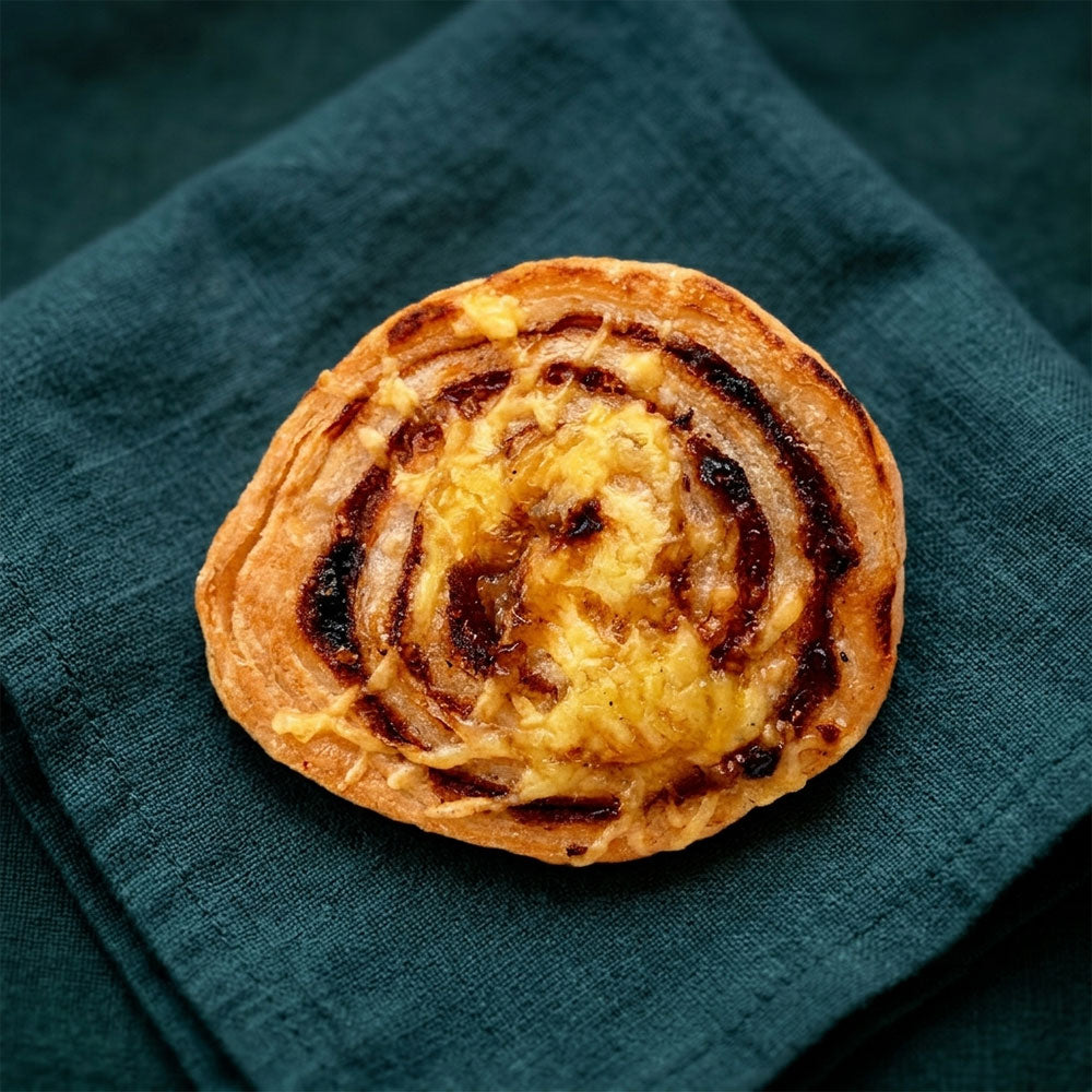 Aranybarna, csigavonalban feltekert sajtos-pizzás csiga enyhén megpirult szélekkel.