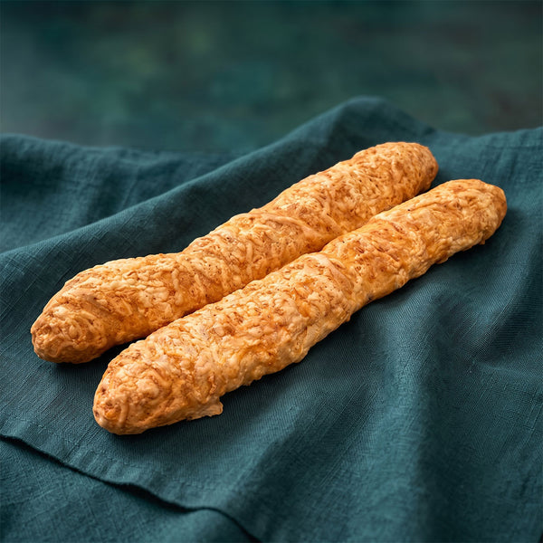 Két darab hosszúkás, aranybarna, ráolvadt sajtos réteggel borított péksütemény rúd.