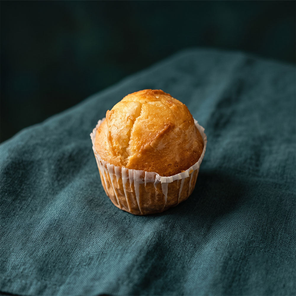 Aranybarna, papírkosárkás vaníliás muffin sötétzöld háttérrel.